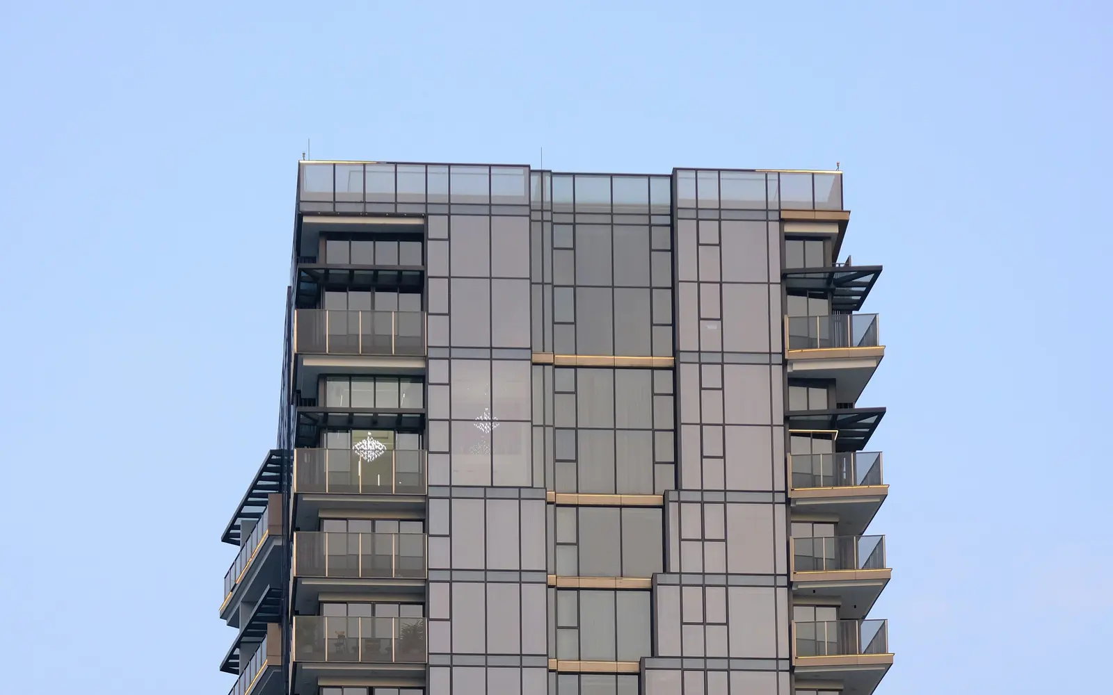A modern residential condominium tower with glass balconies